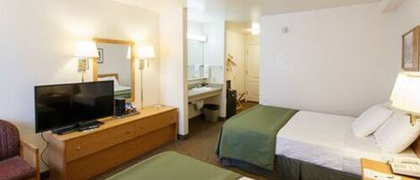 Ein Hotelzimmer mit Bett, Fernseher, Schreibtisch und Stuhl.