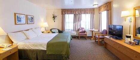 A hotel room with a bed, a desk, a chair, a television, and a lamp.
