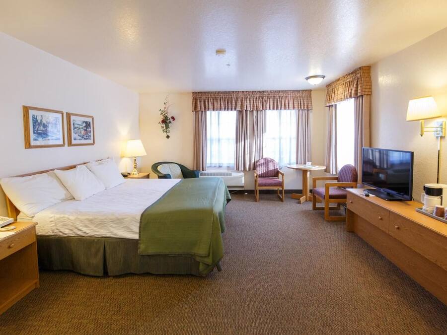 Een hotelkamer met een bed, een bureau, een stoel, een televisie en een lamp.