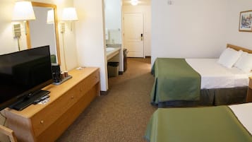 Ett hotellrum med en TV, en byrå i trä, två sängar, en spegel och en dörr.