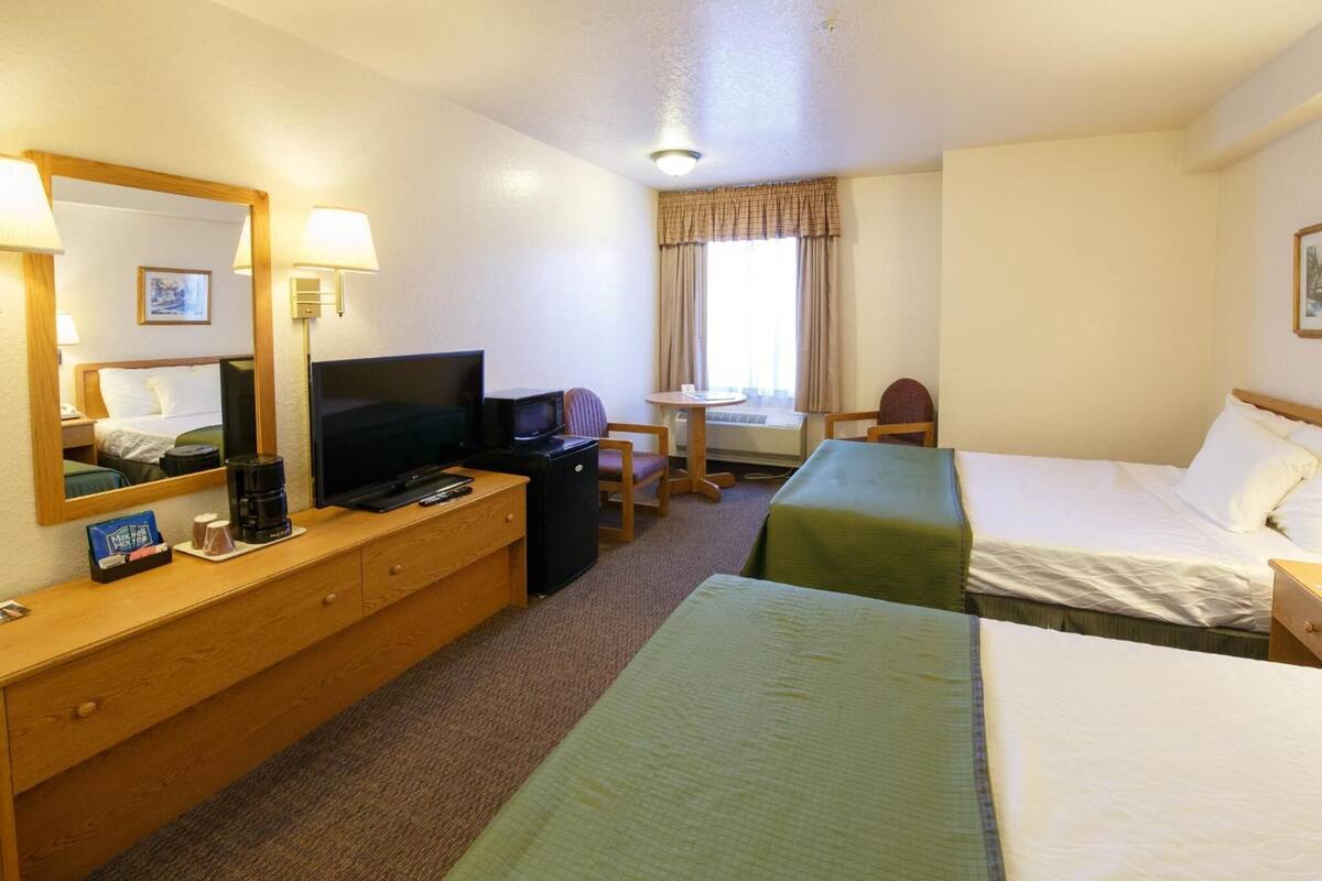 Une chambre d’hôtel comprenant un lit, un bureau avec une télévision, une chaise et une petite table.