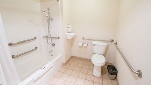 A bathroom with a shower, toilet, and grab bars. - Murphys Inn Motel (Murphys)