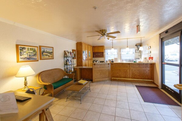 A cozy living room with a sofa, a small table with a lamp, and a kitchenette area.