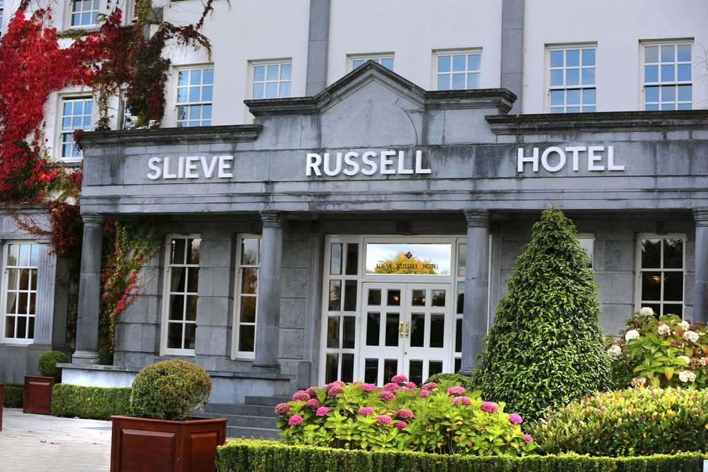 The exterior of the Slieve Russell Hotel with a classic facade, large windows, and a well-maintained garden.