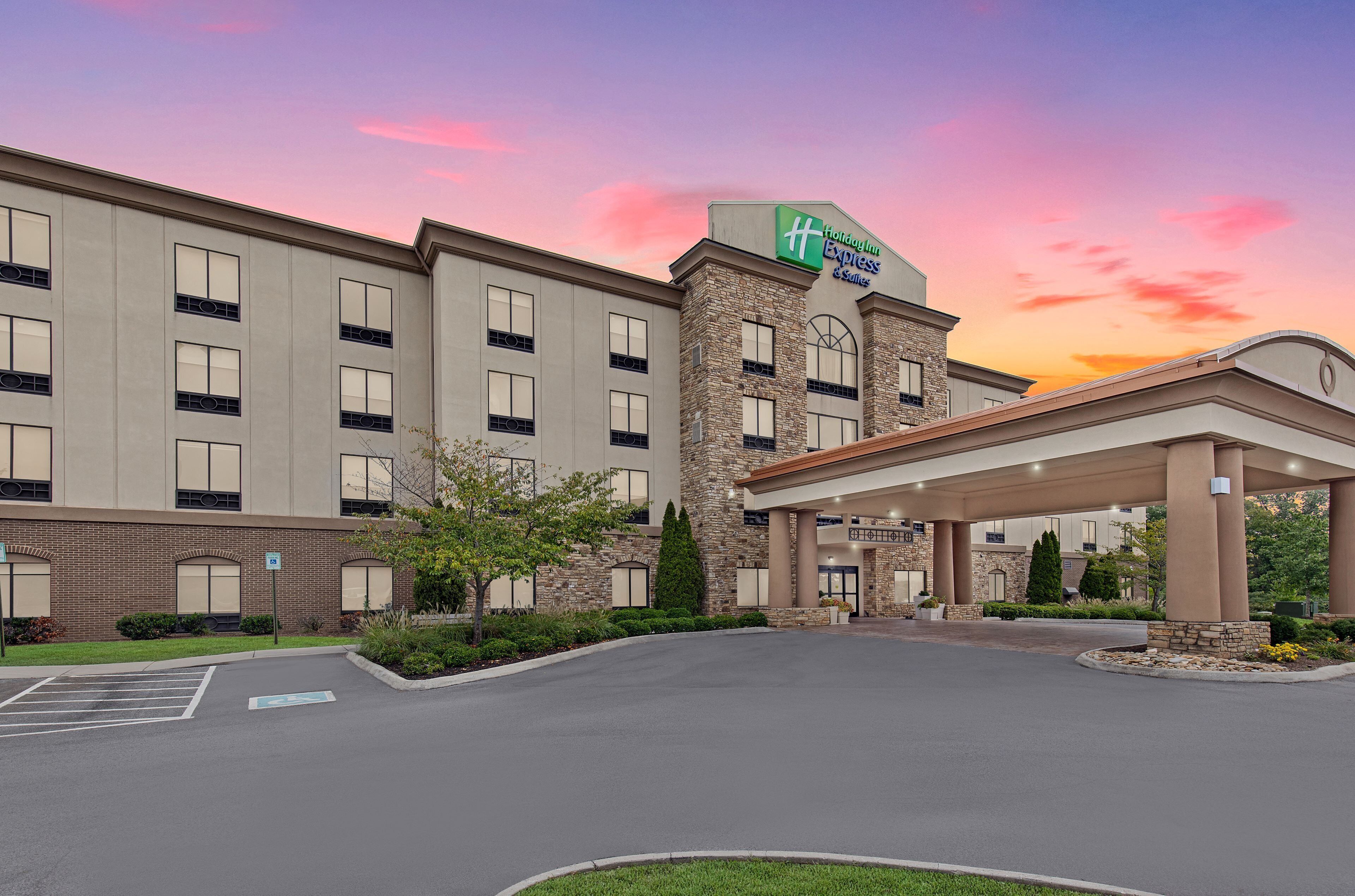 A hotel with a brick facade, a large entrance canopy, and a parking lot.
