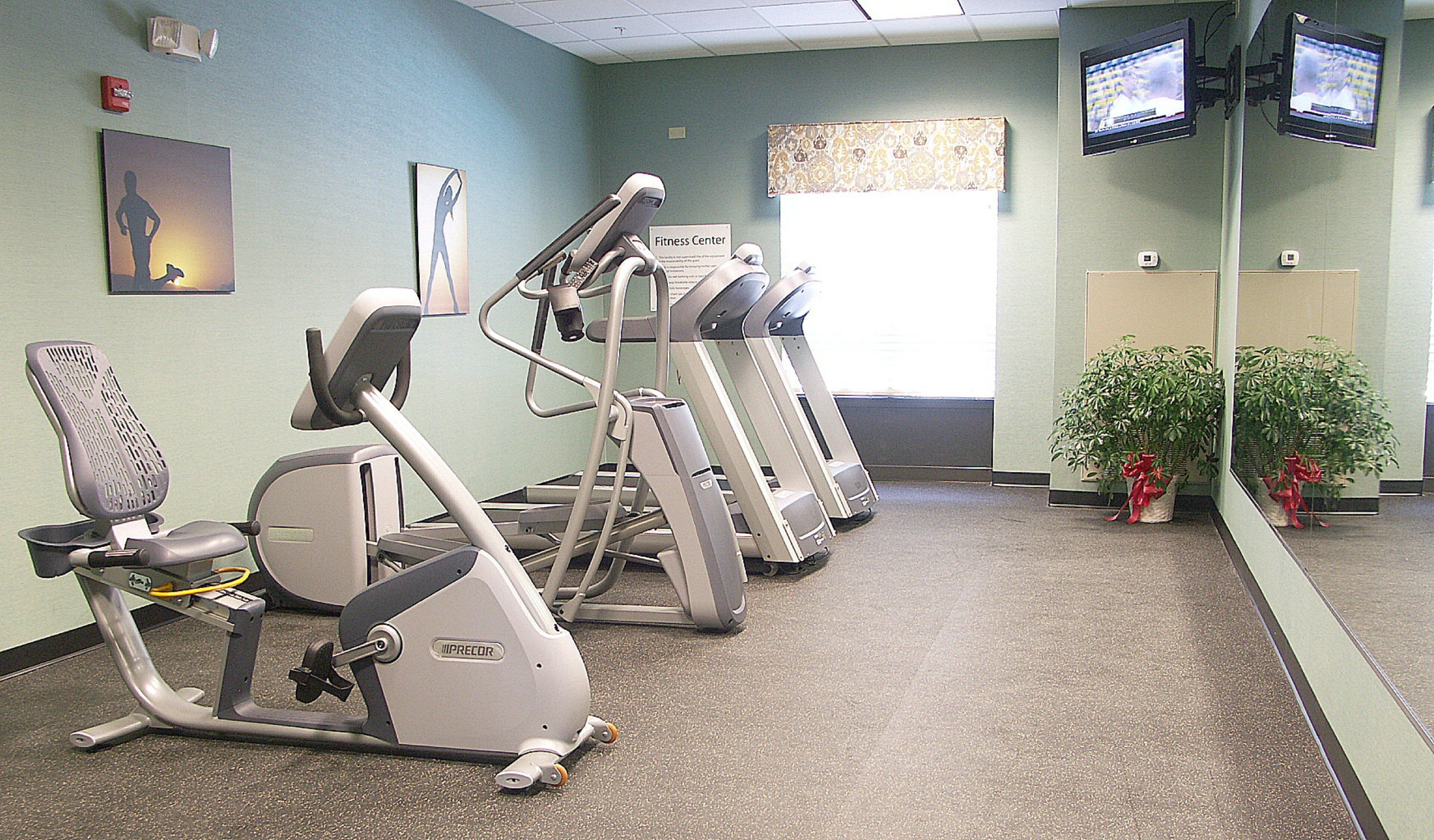 Un gimnasio equipado con cintas de correr, elípticas y una bicicleta estática.