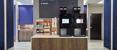 A coffee station with two espresso machines, a coffee dispenser, and a counter with various coffee-related items.