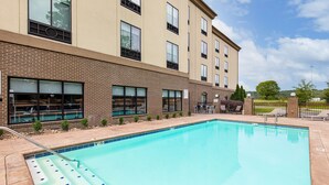 A swimming pool with steps leading into it, surrounded by a brick building with multiple windows and a clear sky. - Holiday Inn Express Cleveland Northwest by IHG (Cleveland)