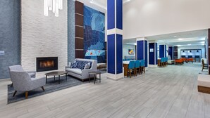 A modern lobby with a fireplace, seating area, and a large wall mural. - Holiday Inn Express Cleveland Northwest by IHG (Cleveland)