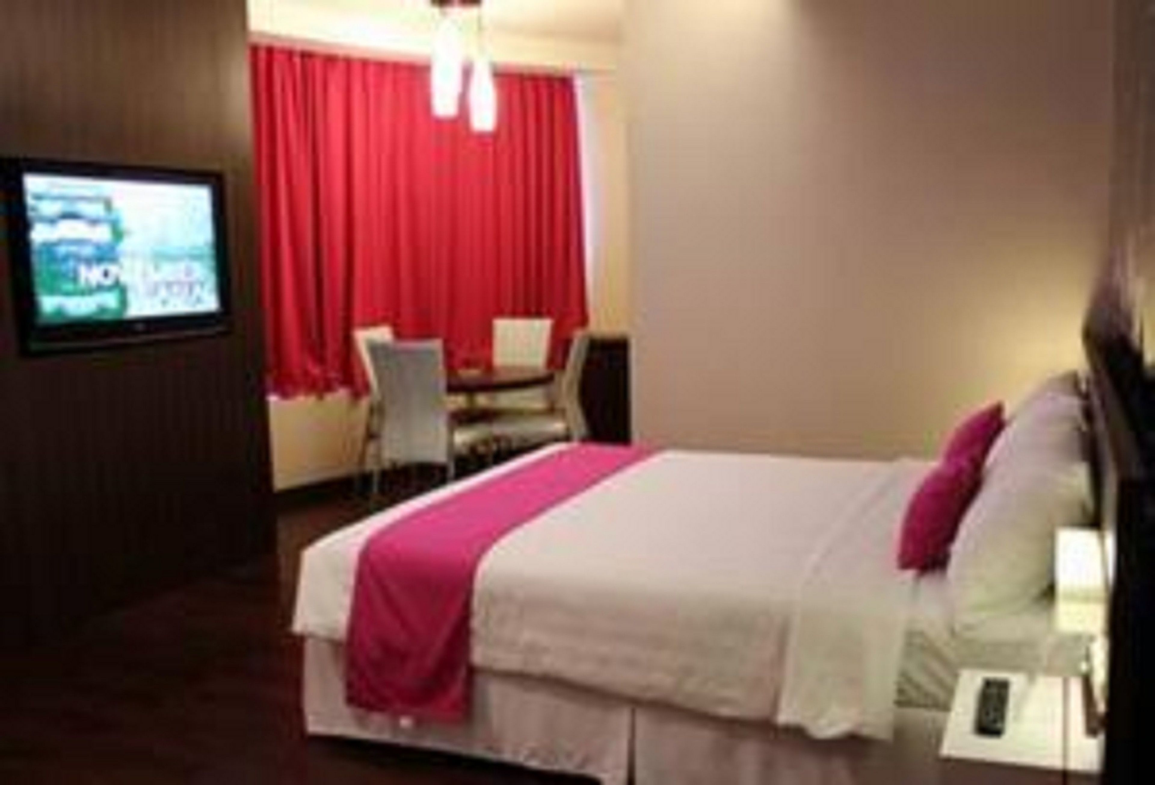 A hotel room with a bed, a TV, a desk, and a chair.