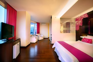 A hotel room with a bed, a TV, a desk, and a seating area.