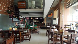 A restaurant interior with wooden tables and chairs, a counter with a menu, and a festive decoration. - Cityscape Hotel (Mandaue)