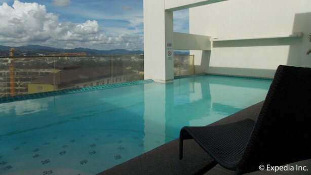 A rooftop infinity pool with a clear view of the cityscape and mountains in the background. - Cityscape Hotel (Mandaue)