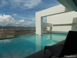 A rooftop infinity pool with a clear view of the cityscape and mountains in the background. - Cityscape Hotel (Mandaue)