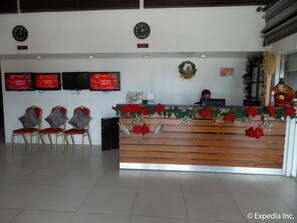 A reception desk with a wooden counter, two clocks, and Christmas decorations. - Cityscape Hotel (Mandaue)