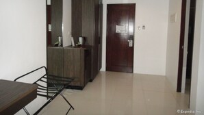 A hotel room with a wooden desk, a chair, a large mirror, and a door with a sign. - Cityscape Hotel (Mandaue)
