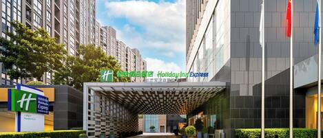 A modern hotel entrance with a check-in desk, a Holiday Inn Express sign, and a large glass facade.