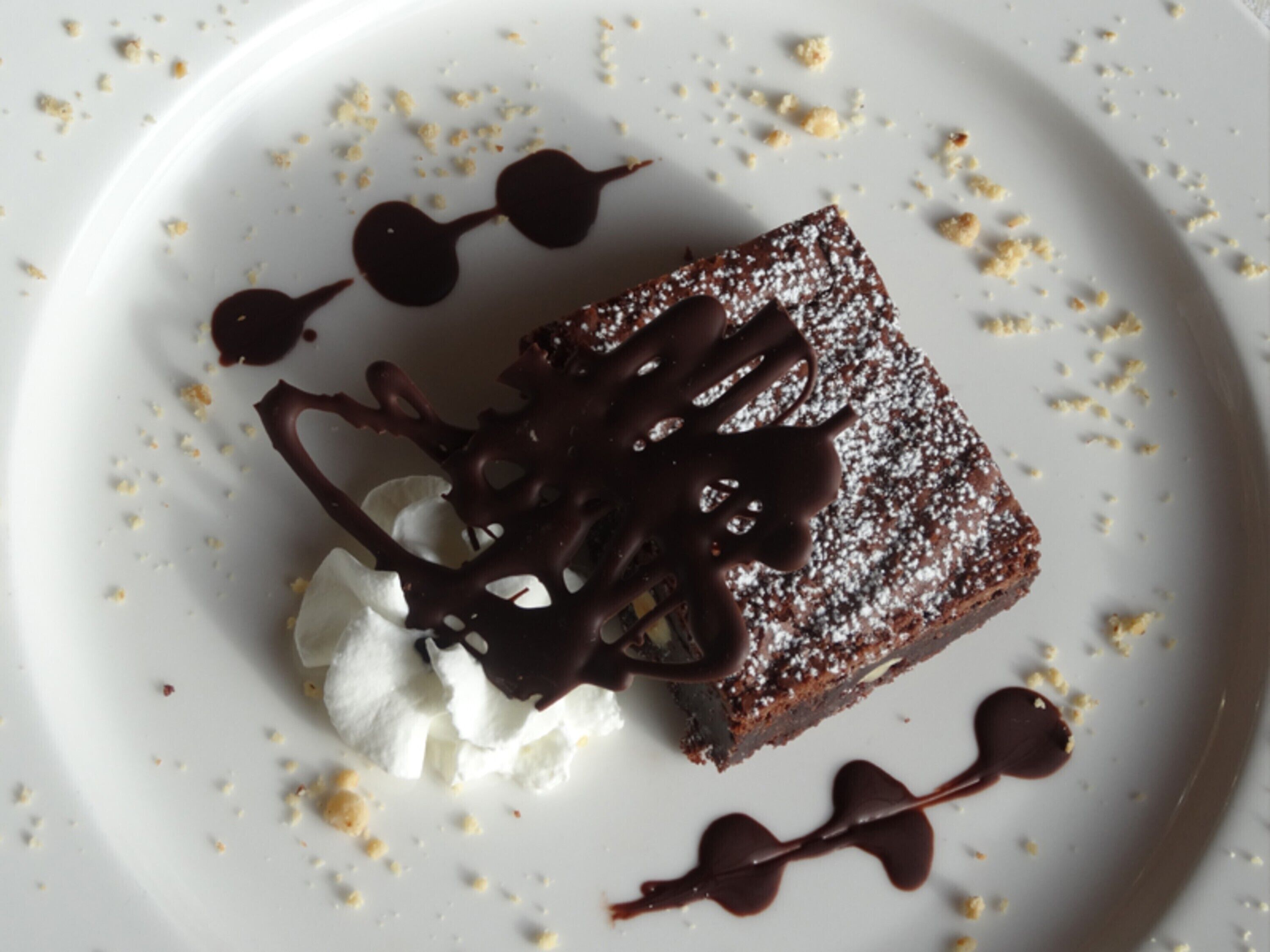 A dessert on a plate with chocolate sauce and crumbs.