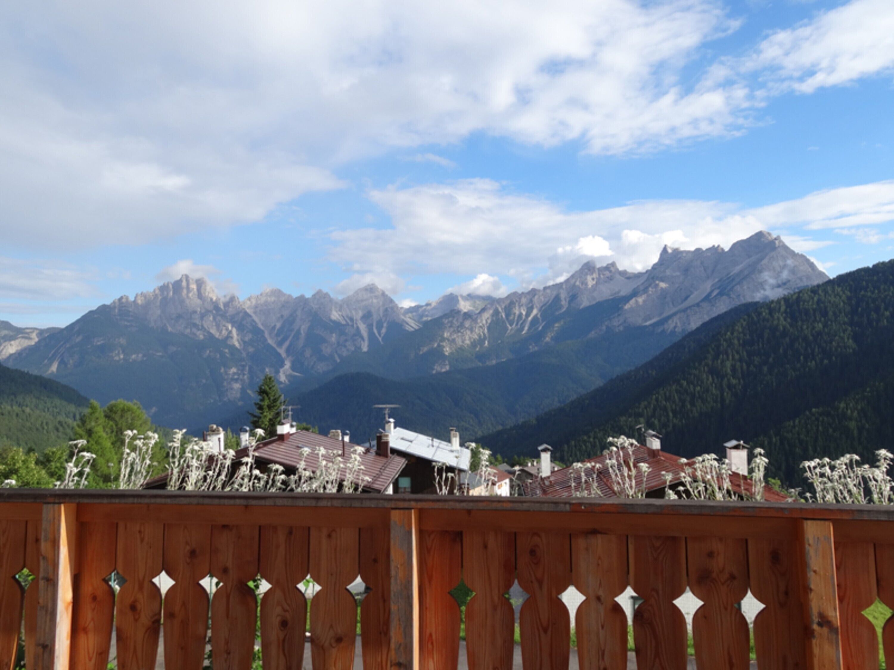 Une vue sur une montagne, avec une clôture en bois au premier plan.