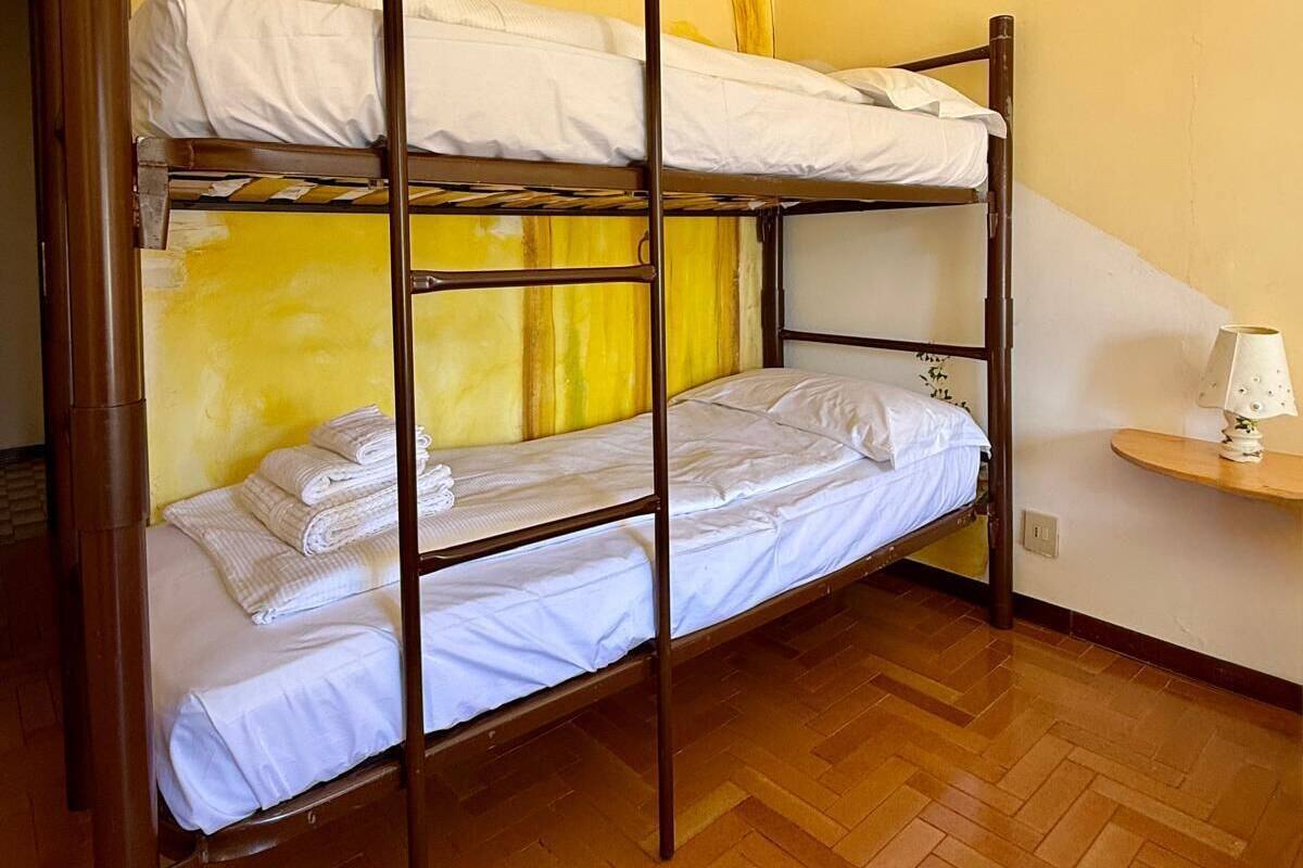 Habitación con literas, suelo de madera y pared amarilla.