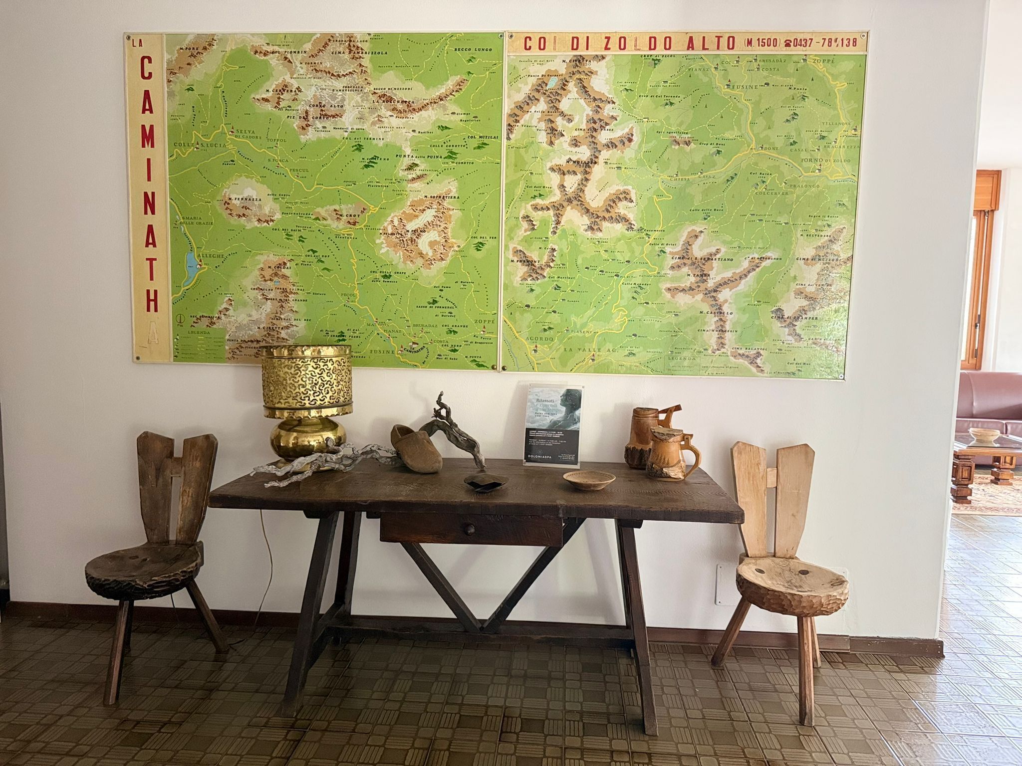 Une pièce avec une table et des chaises en bois, une carte accrochée au mur et une lampe décorative.