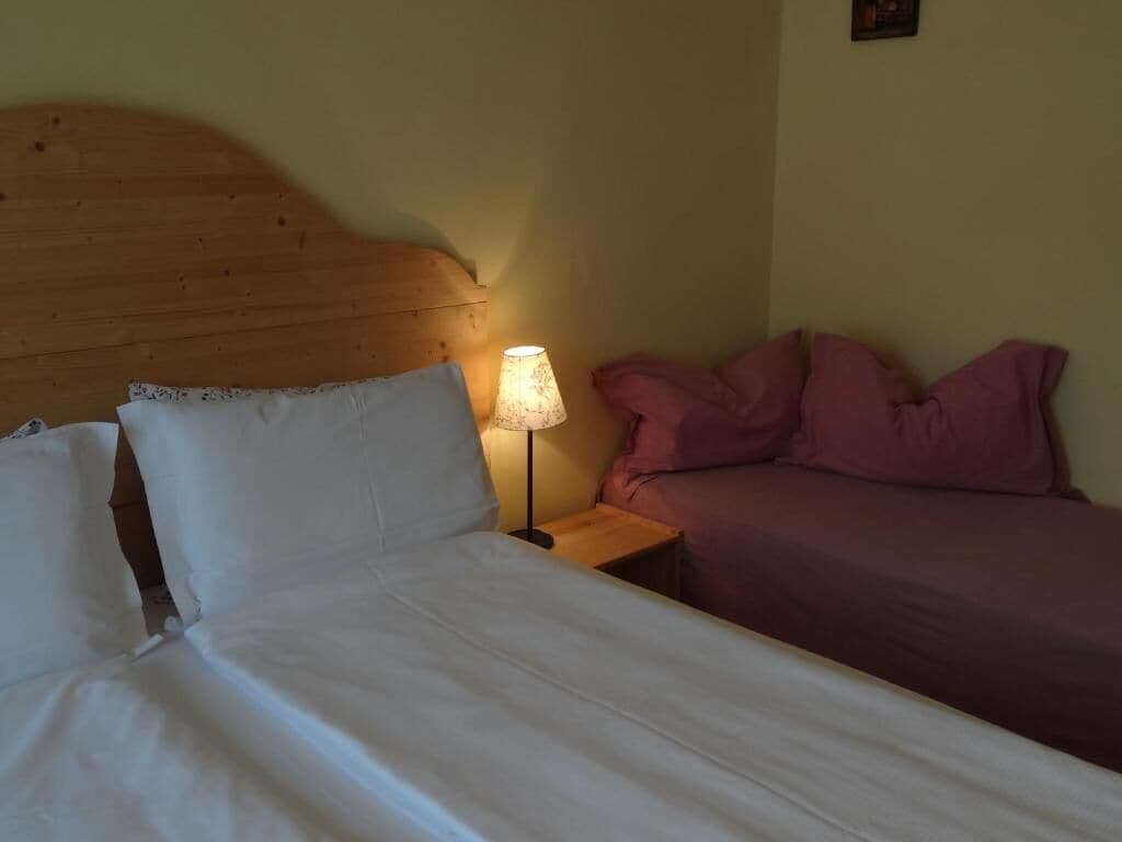 Una habitación con cama de cabecera de madera, lámpara de noche y dos camas con ropa de cama de diferentes colores.