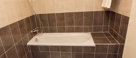Un baño moderno con bañera, baldosas oscuras y un perchero.