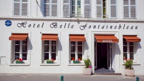 Un edificio blanco con el letrero "Hotel Belle Fontainebleau" y numerosas ventanas con toldos marrones.