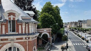 Vista de la calle con un edificio de ladrillo, ventanas de arco y tejado de tejas.