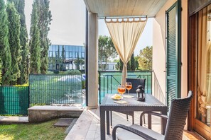 An outdoor patio with a table and chairs, a glass door, and a view of the surrounding area.