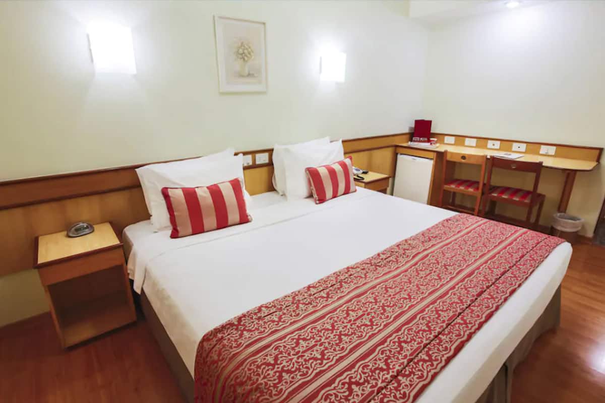 A hotel room with a large bed, a desk, and a chair.