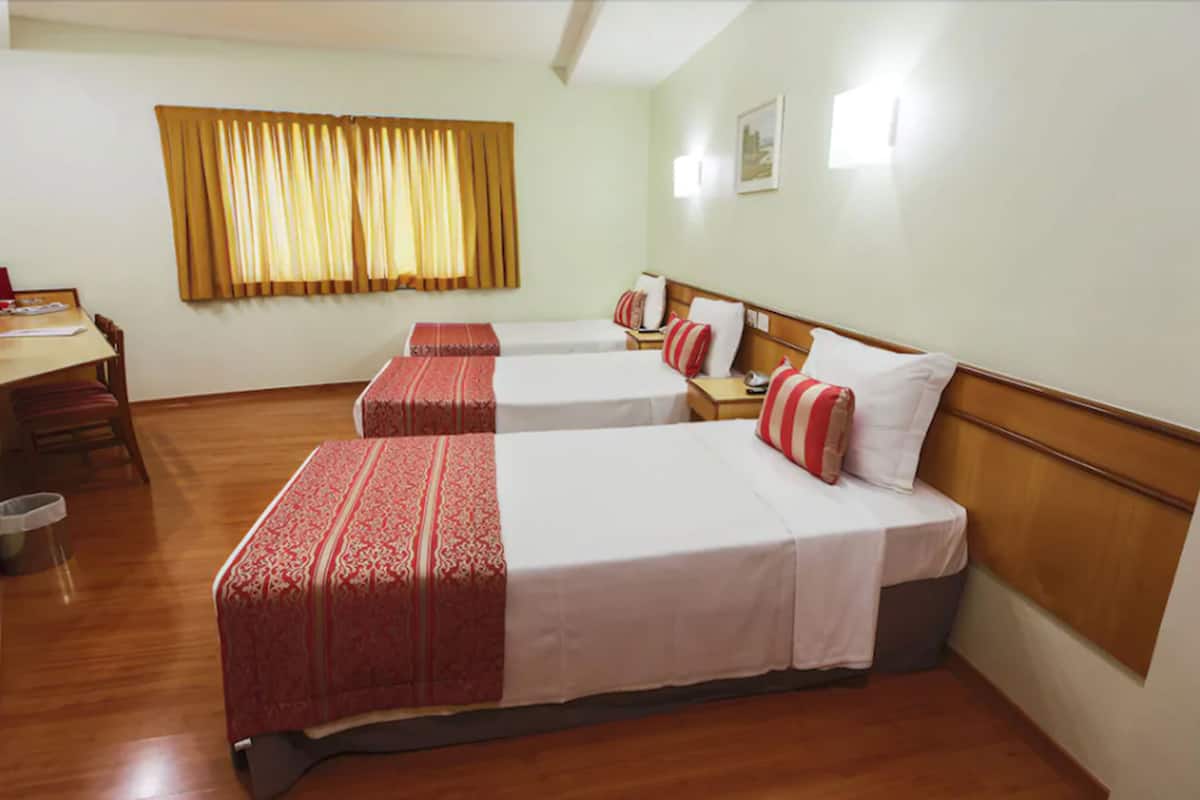 A hotel room with two single beds, a wooden desk, and a chair.