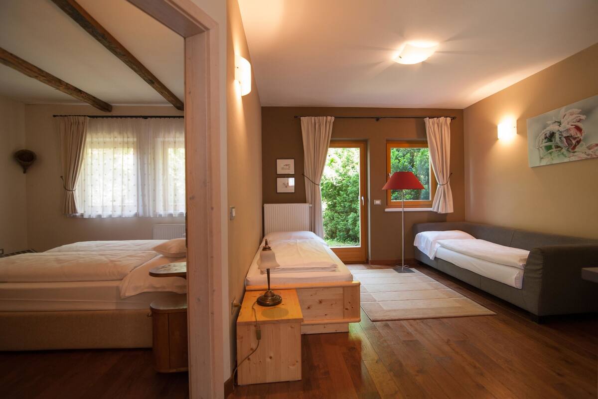 Een kamer met twee bedden, een bank, een lamp en een raam met gordijnen.