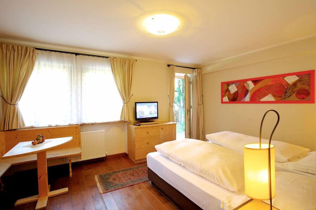 Een slaapkamer met een bed, een bureau, een televisie en een lamp.