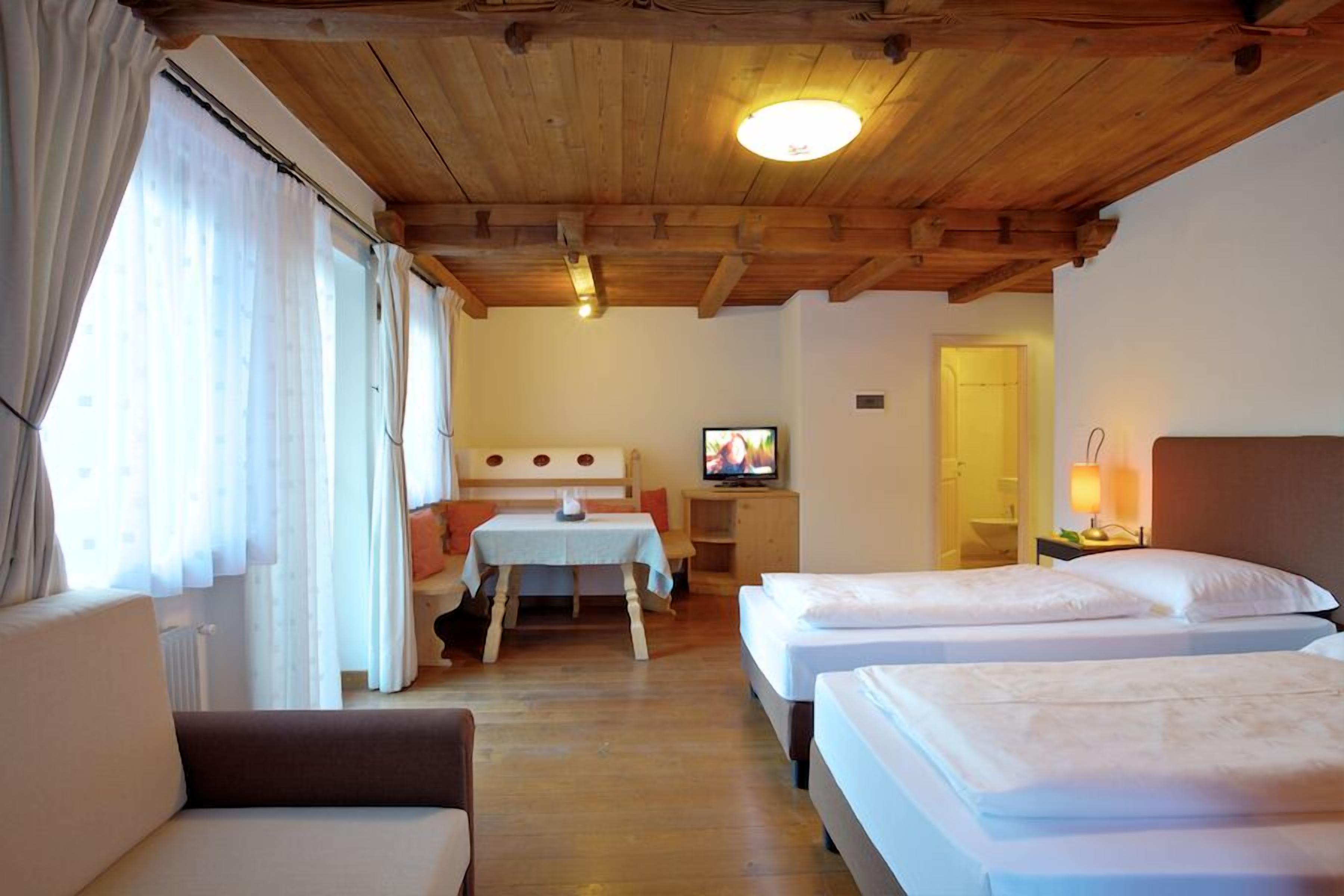 A cozy room with wooden beams, two beds, a TV, and a small table.