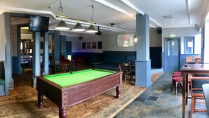Ein Billardraum mit Billardtisch, Stühlen und einer Bar.