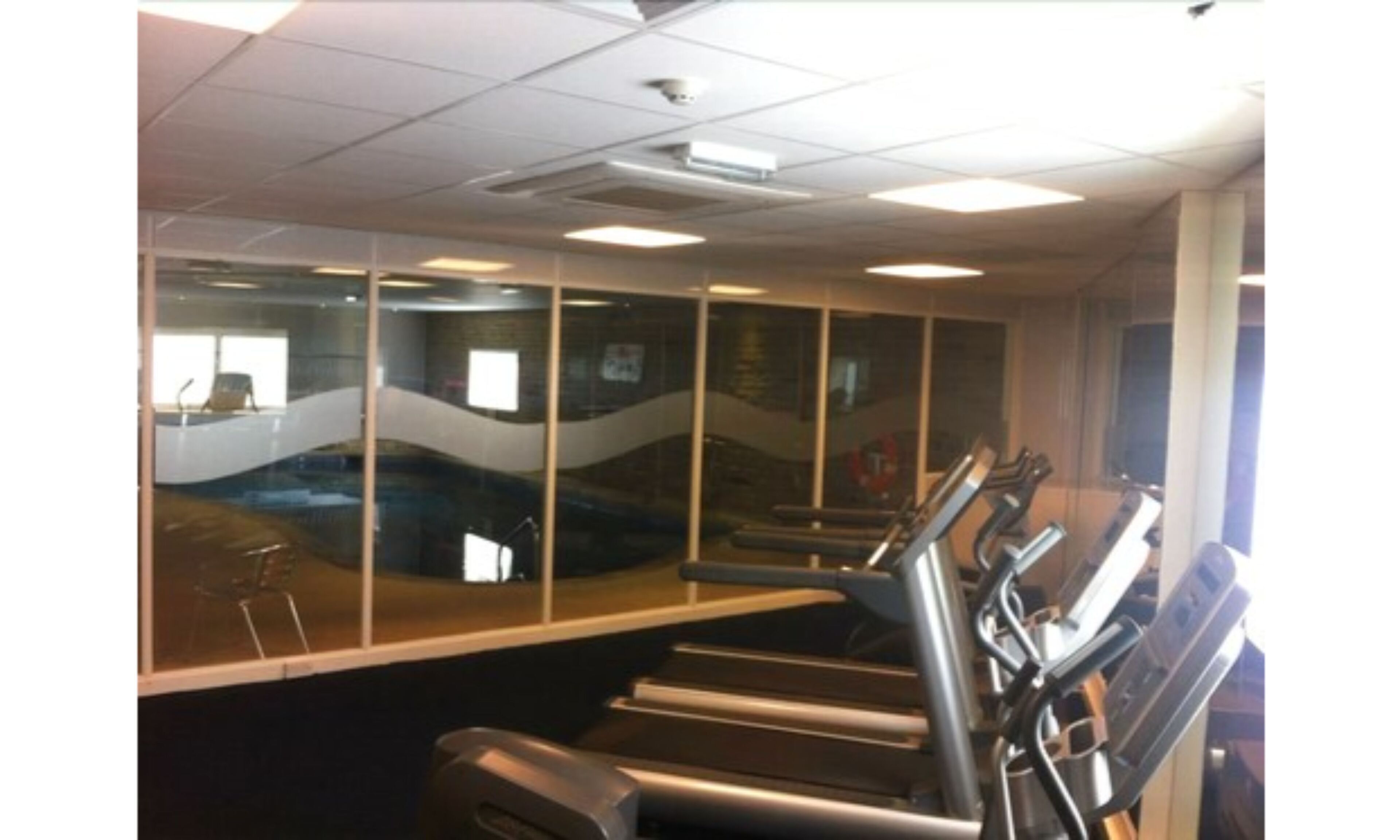 A gym with treadmills, exercise equipment, and large windows.