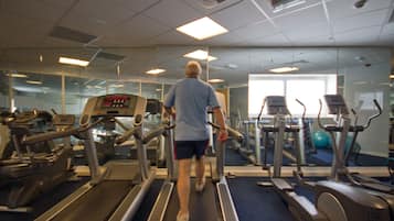 A gym with treadmills, exercise bikes, and a mirrored wall.