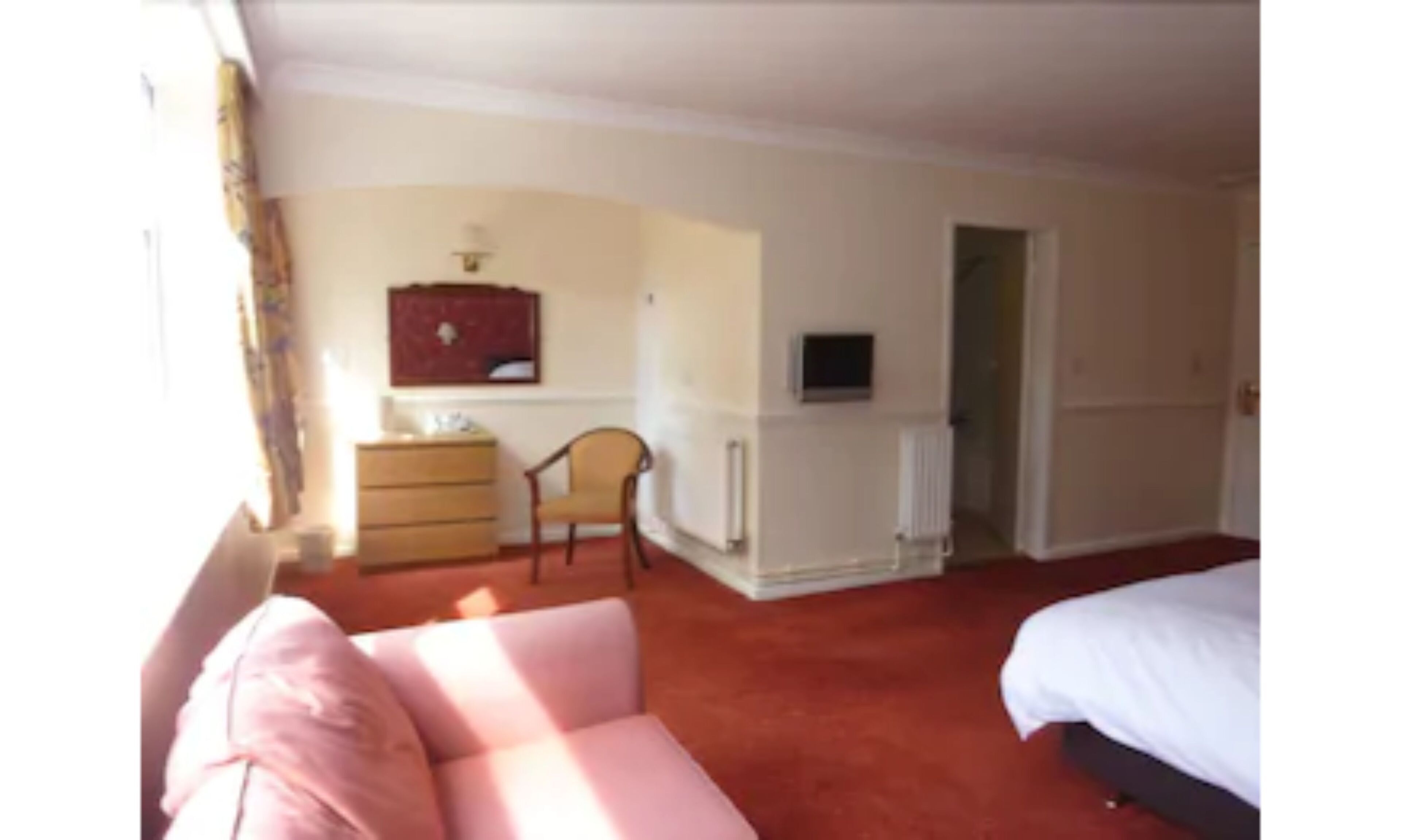 A hotel room with a bed, a sofa, a dresser, a chair, and a television.
