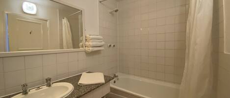 A bathroom with a sink, mirror, and a bathtub with a shower curtain.