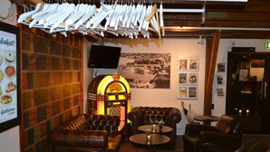 A cozy lounge area with leather sofas, a jukebox, and a wall with various posters. - Park Hotel Motala (Motala)