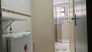 A corridor with a refrigerator, a door leading to a bathroom, and a tiled floor. - Hotel Seibt (Foz do Iguaçu)