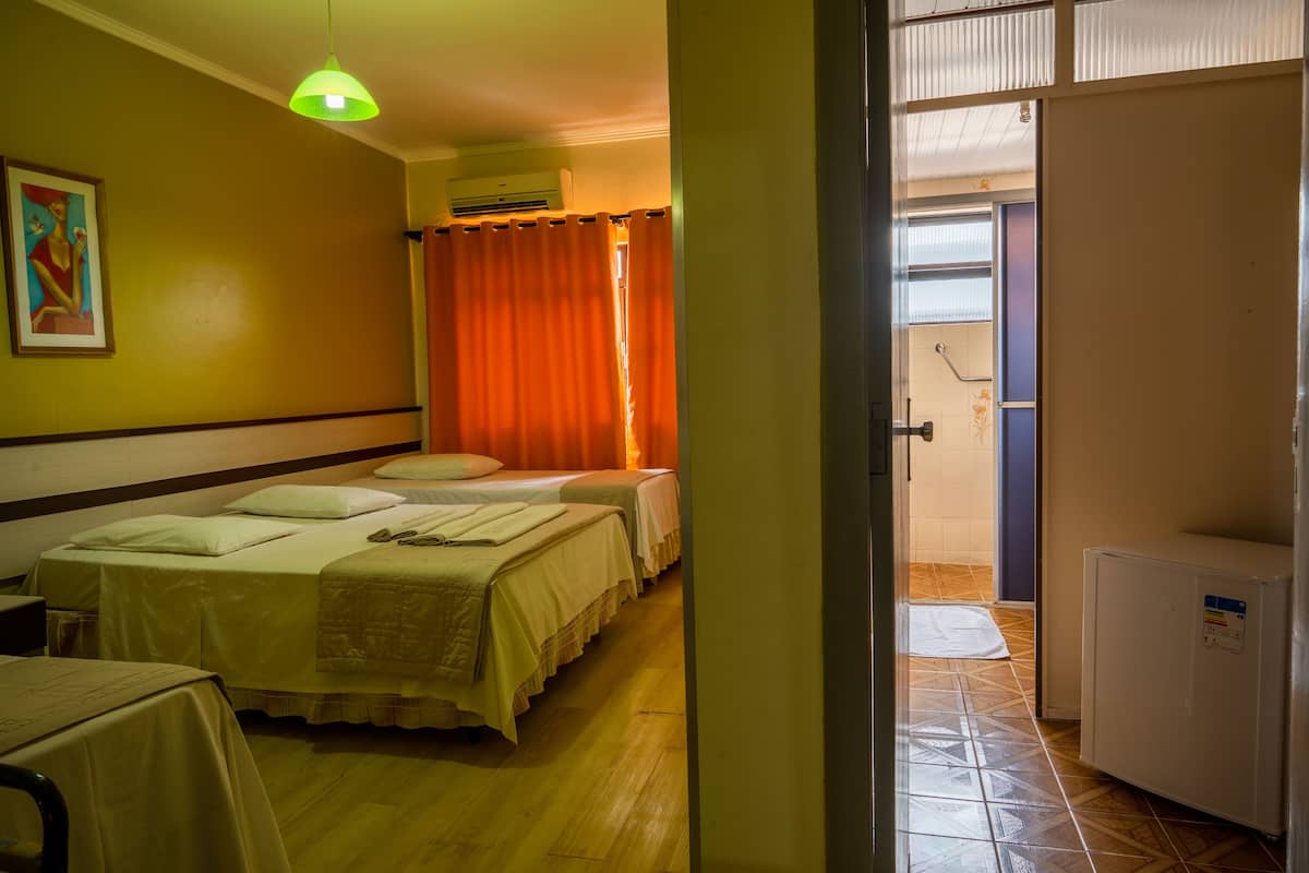 Habitación de hotel con dos camas, una mesita, un refrigerador y un equipo de aire acondicionado.