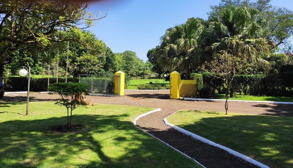A pathway leading to a gated entrance surrounded by lush greenery and trees. - Ipelandia Park Golf Hostel (Foz do Iguaçu)