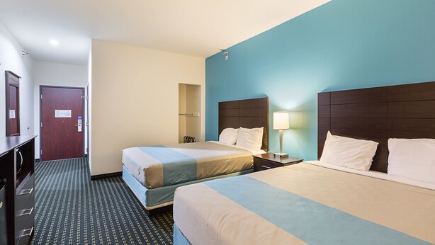 Une chambre d’hôtel avec deux lits, un bureau, une lampe et une armoire.