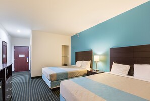 A hotel room with two beds, a desk, a lamp, and a wardrobe. - Budget Inn and Suites (Ganado)