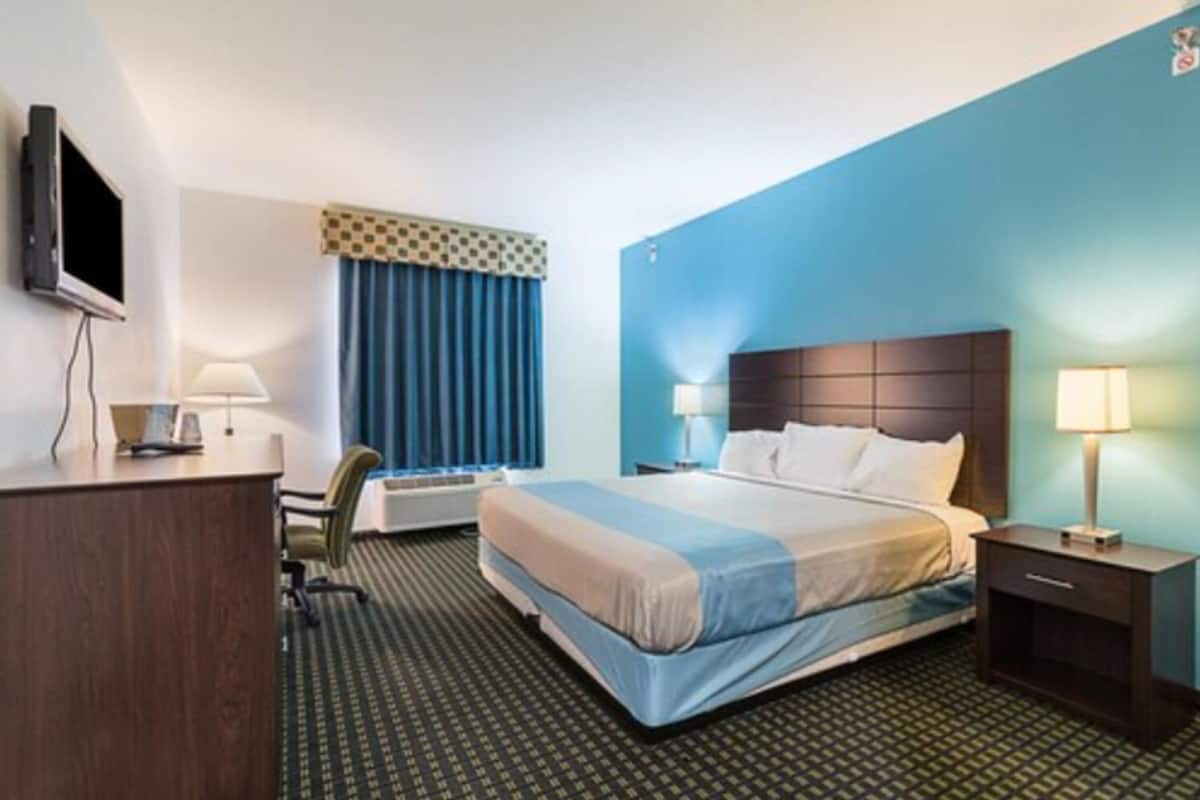 A hotel room with a bed, desk, chair, and a television.