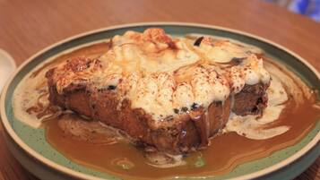 A plate of food with a creamy topping, a wooden table, and a cup in the background.