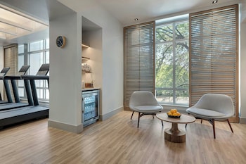 A modern hotel room with a large bed, a sofa, a TV, and a balcony with curtains. at Live Oak, Charleston Historic District, a Tribute Portfolio Hotel