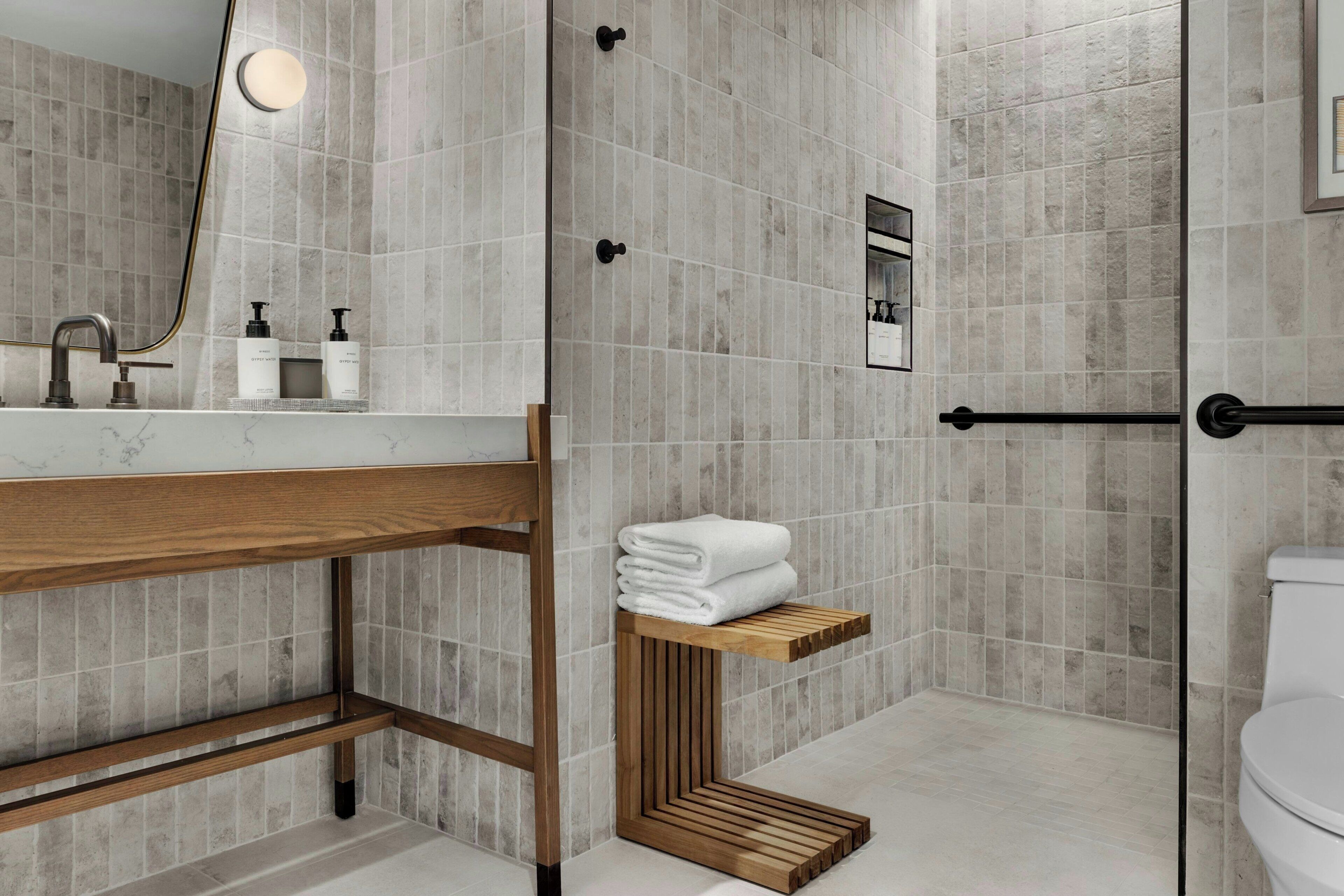 Ein modernes Badezimmer mit Marmorwaschbecken, Holzwaschtisch, einer Duschkabine aus Glas und einer Toilette.
